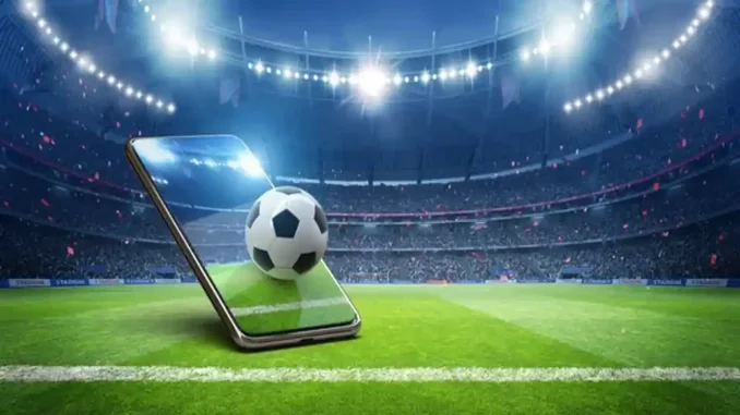 Ilustração de celular com bola de futebol em um estádio iluminado.